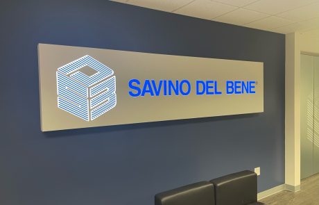 LED Lobby Sign on a dark blue wall, gray background with bright blue letters, "Savino Del Bene".