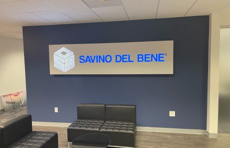LED Lobby Sign on a dark blue wall, gray background with bright blue letters, "Savino Del Bene".