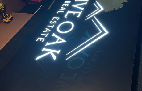 Indoor local signage, black background with white lettering, Live Oak Real Estate