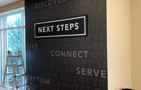 Indoor wall sign black background white letters, "Next Steps"