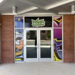 Outdoor Window Decal Sign above two doors in green letters that read Dank Burrito