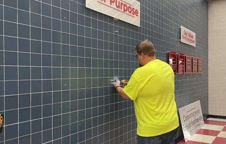 Indoor tile wall in dark blue with white stripes. White signs, red letters on wall, Our Purpose and Our Values