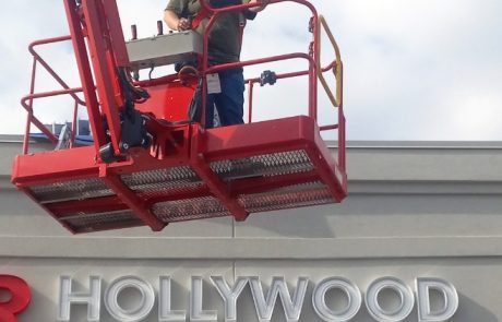 Construction Worker, red crane, working on the side of a building. Off-white building with white letters, Hollywood