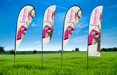 Event Decal, White Background, Pink letters, Zoom Flex, In a bright green field with a bright blue sky background.