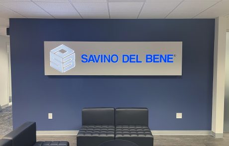 LED Lobby Sign on a dark blue wall, gray background with bright blue letters, "Savino Del Bene".